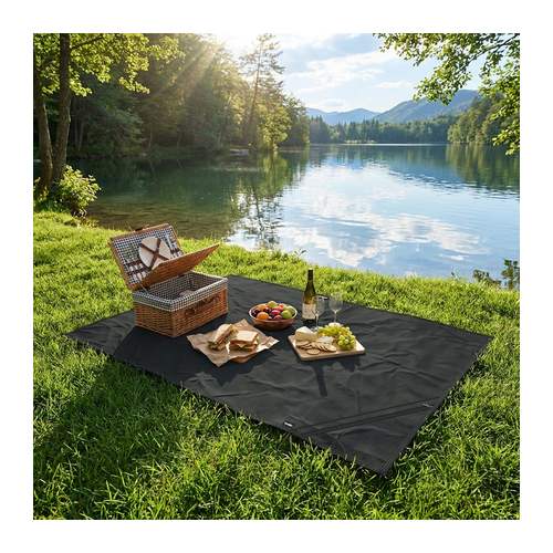 Camping blanket laid on grass beside a lake and set with a picnic hamper, plates and glasses, Singapore