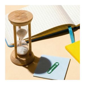 Print mock-up showing a logo laser engraved on the bamboo cap of a five minute sand timer on a desk, Singapore