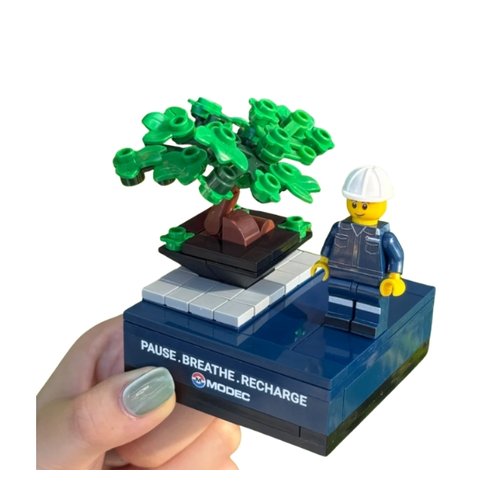 Custom brick minifigure in company uniform beside a bonsai on a printed logo base - corporate gift Singapore